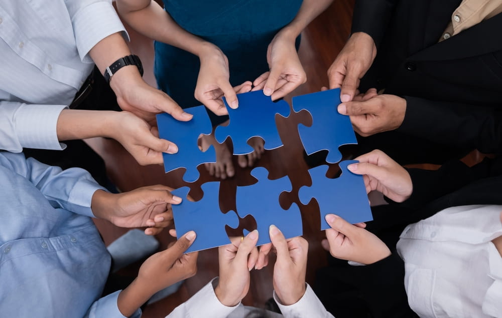 Team assembling puzzle pieces to symbolize merger integration and business alignment