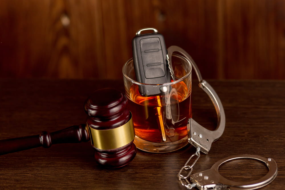 Florida DUI penalties concept showing gavel, handcuffs, and car keys in a glass of whiskey representing license suspension and criminal charges.