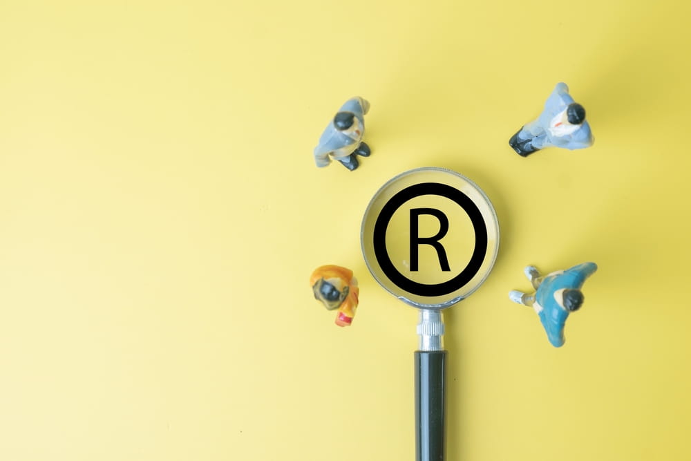 Magnifying glass over registered trademark symbol representing intellectual property and content licensing rights