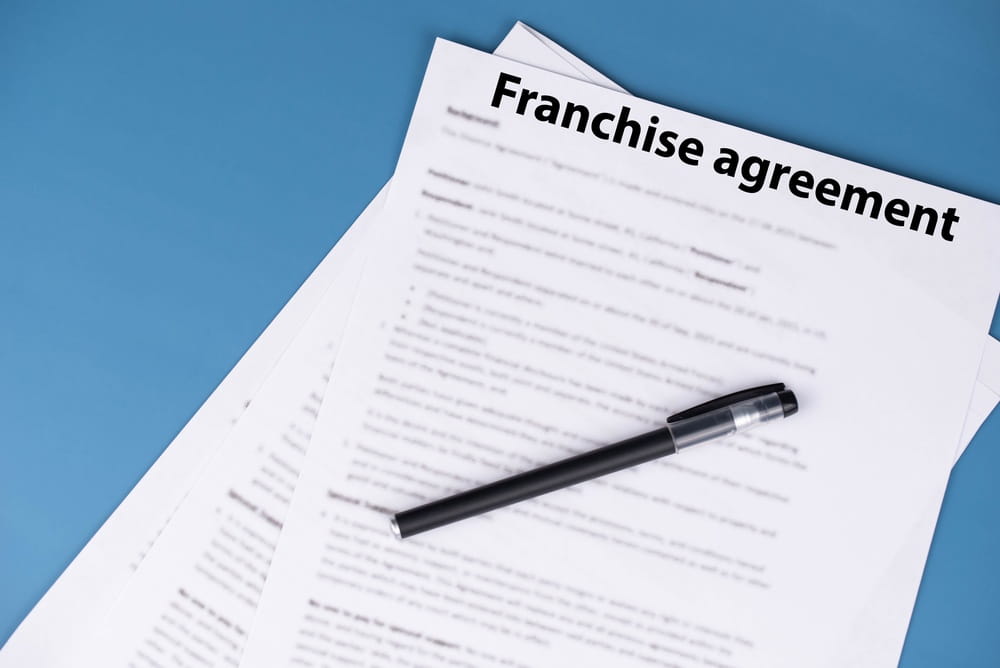 Franchise agreement documents with a pen on a desk, illustrating franchise contracts, compliance, and dispute prevention strategies.