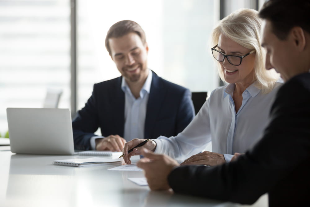 Business professionals reviewing and signing documents during a franchise planning meeting, illustrating franchise development and legal consultation.