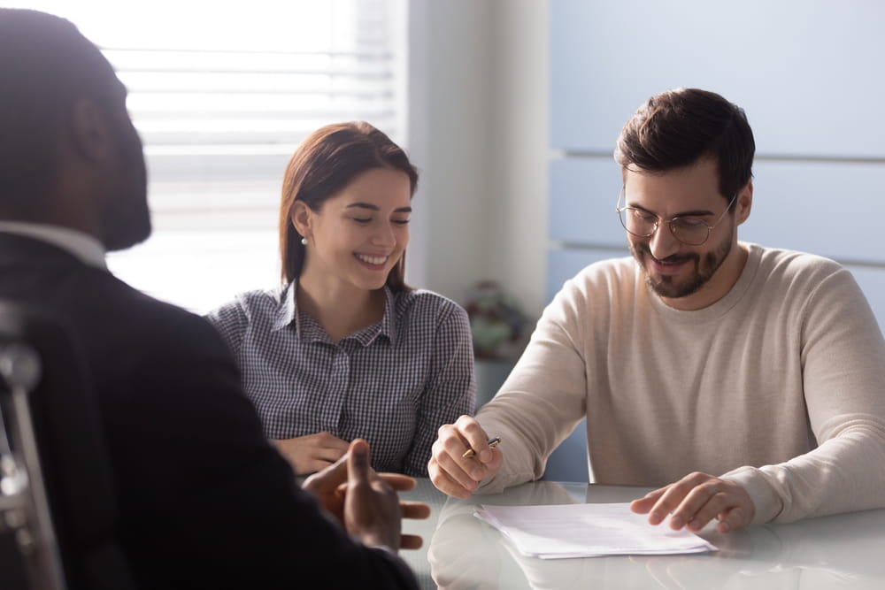 Couple meeting with a business advisor to discuss franchise contracts and disclosure documents before purchasing a franchise.